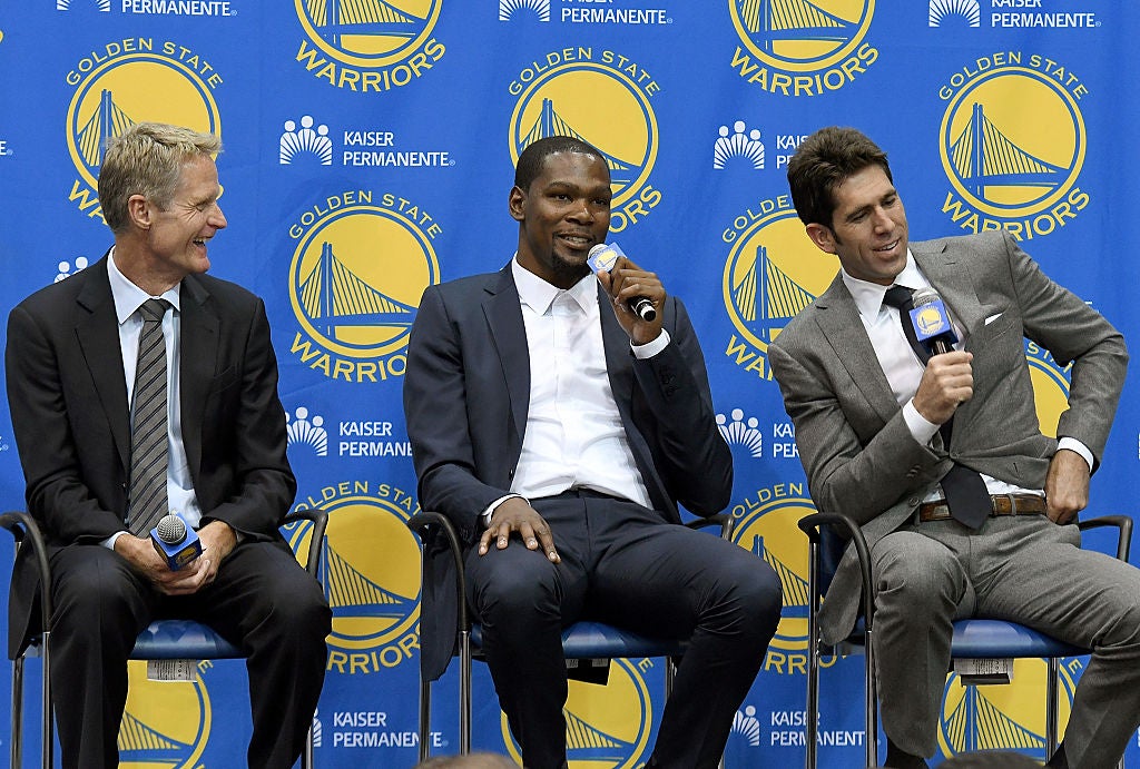 Head coach Steve Kerr of the Golden State Warriors sits with Kevin Durant and general manager Bob Myers while they speak to the media during the press conference where Durant was introduced as a Golden State Warrior after they signed him as a free agent on July 7, 2016 in Oakland, California.