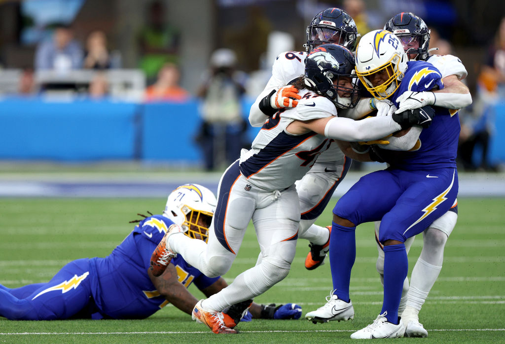 INGLEWOOD, CALIFORNIA - DECEMBER 10: Joshua Kelley #25 of the Los Angeles Chargers is tackled by Josey Jewell #47, Alex Singleton #49 and Baron Browning #56 of the Denver Broncos during the third quarter at SoFi Stadium on December 10, 2023 in Inglewood, California. 