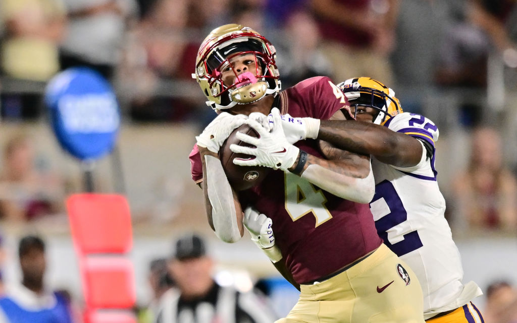 Keon Coleman #4 of the Florida State Seminoles catches a pass against Duce Chestnut #22 of the LSU Tigers in the first half of a game at Camping World Stadium 